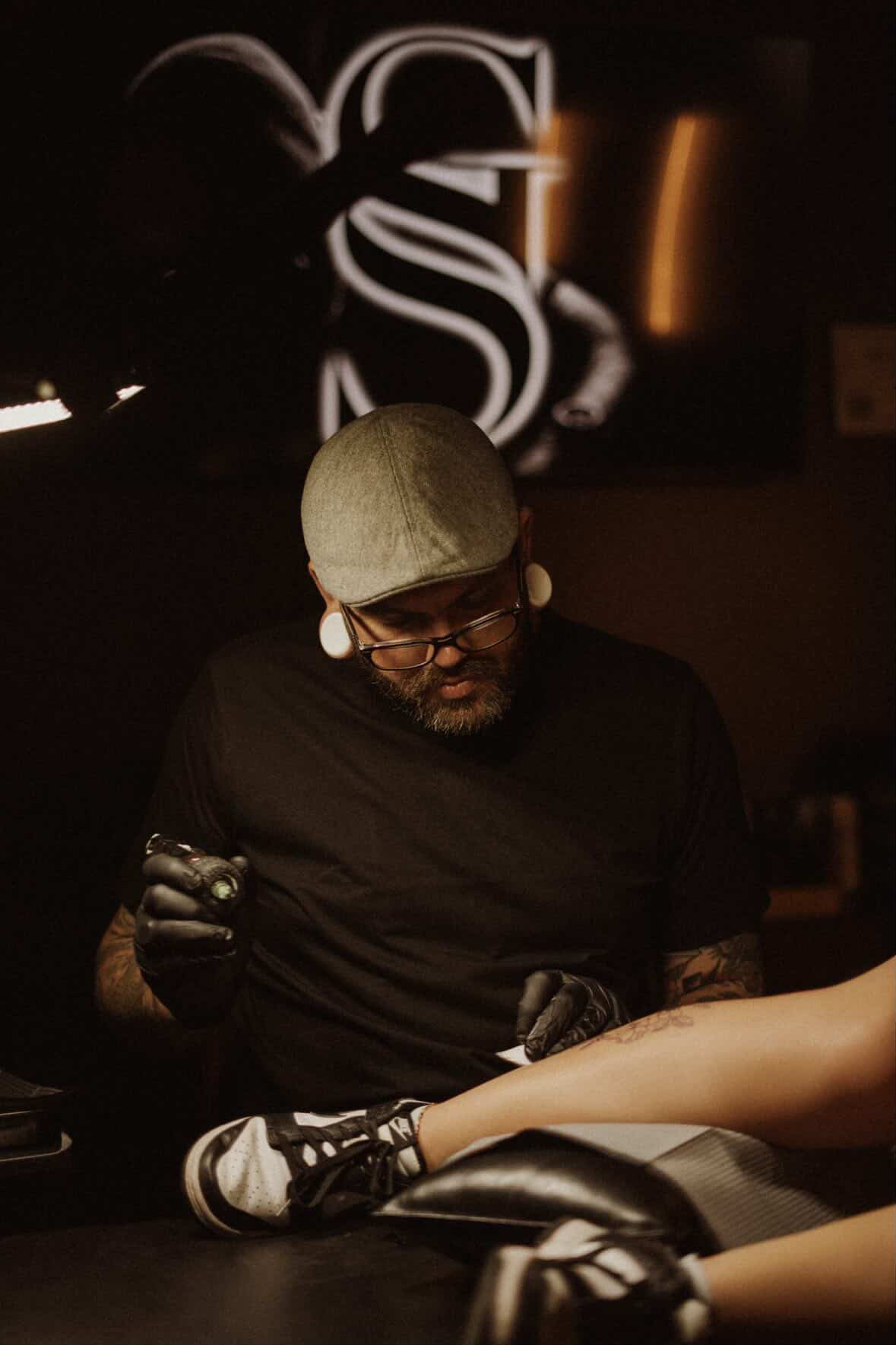 George tattooing a client beneath the Sir George monogram
